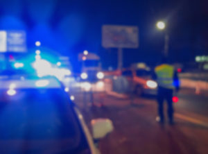 Unrecognizable blurry police car lights and police force officer on night road background, crime scene, night patrolling the city.